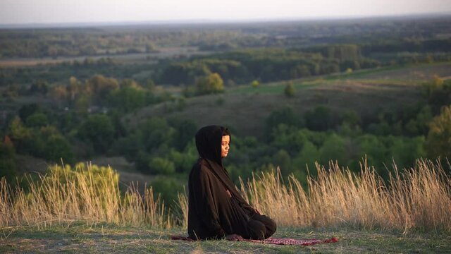 4k Black muslim woman praying on the carpet. Solat praying on the beautiful hill. Salah traditional pray.