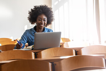 Young black female student sitting in classroom and preparing for lecture. 