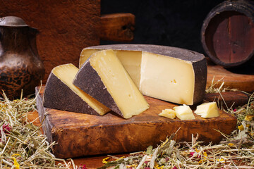 Traditioneller gereifter Bergkäse aus den Alpen angeboten als Laib und Stück in einer rustikalen...