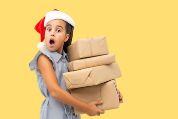 little girl in santa hat with boxes on yellow background.
