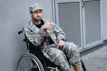 depressed and disabled military man sitting in wheelchair with bottle of alcohol