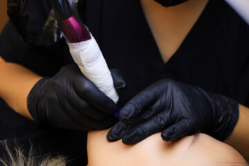 the tattoo artist bent down in front of the model and performs permanent lip makeup held the model by the lips with his fingers