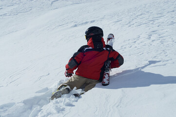Chłopiec z nartami leży w głębokim śniegu. Alpy, wysokie góry. Śnieg daje przyjemny chłód po wyczerpującym zjeździe na nartach.  © Tomasz