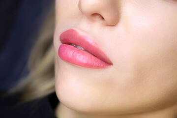 close-up of the beautiful lips of a young model with a lip tattoo