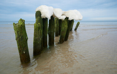 Morski krajobraz zimowy. Czapy śnieżne na słupach i kamieniach, falochronu. © Tomasz