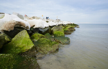 Morski krajobraz zimowy. Czapy śnieżne na słupach i kamieniach, falochronu. © Tomasz