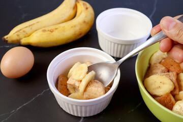 Hand Holding Spoon Putting the Mixture into a Bowl for Baking Banana Bread Pudding	