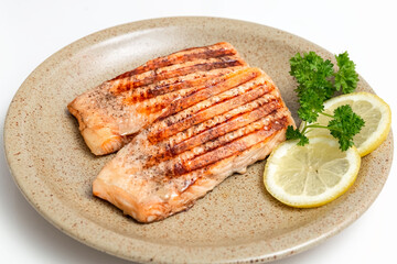Grilled trout fish and lemon slices on a plate. Healthy, delicious homemade food. Photo