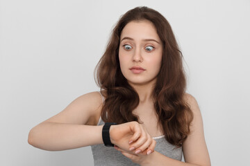 Fototapeta premium A young girl with long hair looks at her wrist watch in surprise