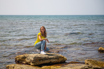 a beautiful woman is sitting on a stone of the Caspian Sea