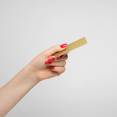 Plastic gold credit card in a woman's hand, red nail polish