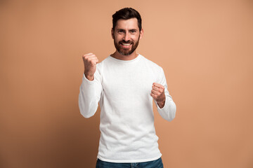 Portrait of ecstatic brunette man with beard showing yes i did it gesture and rejoicing copy space...