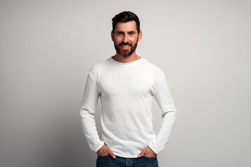 Portrait of happy smiley bearded man with white shirt against light gray background and smiling to the camera. Studio shot. People emotions concept