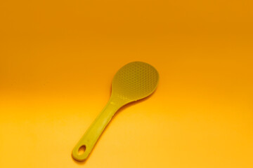 Yellow plastic rice spoon isolated on orange background
