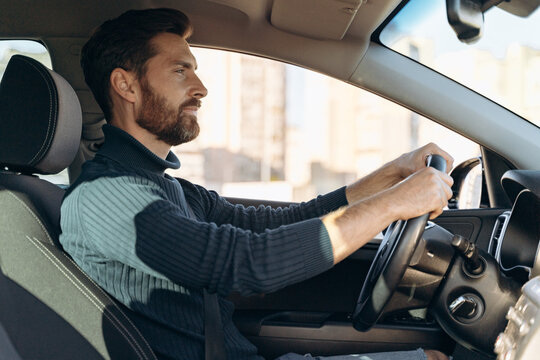Side view of the serious confident man riding at the car and feeling confident while looking at the road during driving. Stock photo