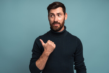 Portrait of happy excited man with beard pointing side with his finger, find out solution or idea,...