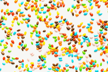 Colored dragee on a white background. Bright candies. Seeds in glaze. Colored background.