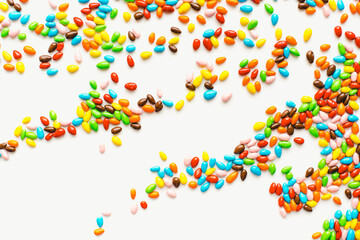 Colored dragee on a white background. Bright candies. Seeds in glaze. Colored background.