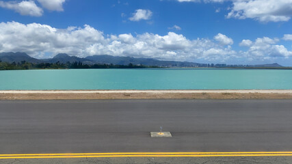 Honolulu Airport reef runway view of blue sea with dense trees on coastline under blue cloudy sky