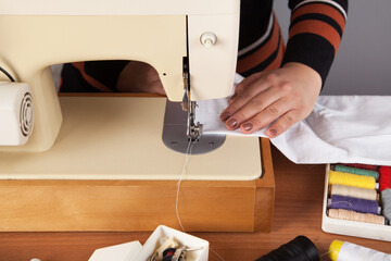 Caucasian woman sews with a sewing machine.