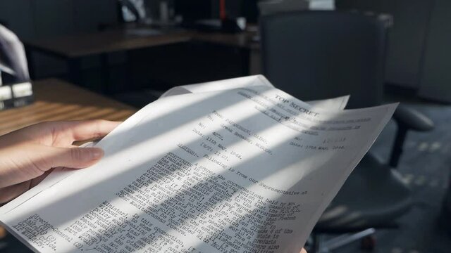 An undercover spy woman examines confidential documents. Female hands leafing through confidential documents