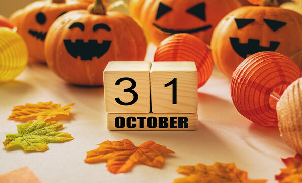 Wooden cubes with the numbers 31 october and pumpkins on table with white background. Halloween celebration concept