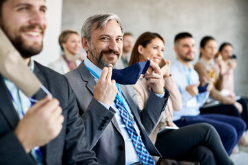 Obraz premium Happy businessman and his associates take off their face masks during education event in board room.