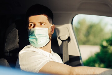 man in a protective medical mask driving a car, the concept of preventing the spread of an epidemic