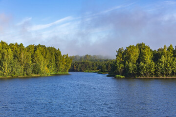 Scenic river landscape with green trees in early autumn