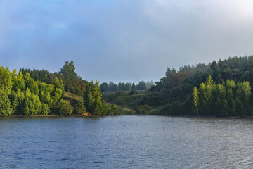 Naklejka premium Scenic river landscape with green trees in early autumn