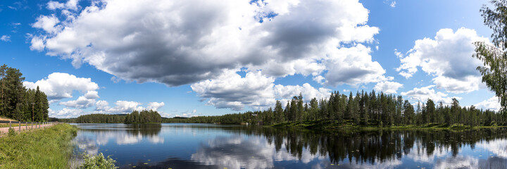 travel sweden and scandinavia, beautiful lake covered with trees and blue sky and white clouds above