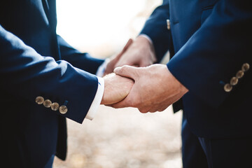Two grooms holding hands during wedding ceremony