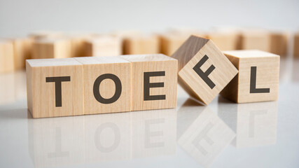 word TOEFL on wooden cubes, gray background