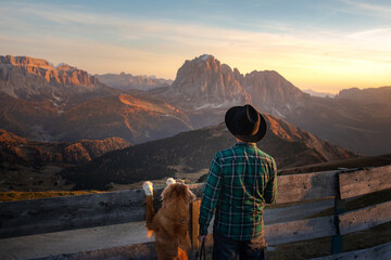 a man with dog looking at the mountains. Dolomites Alps. hiking, relax. Nova Scotia Duck Tolling...