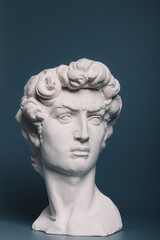 Fototapeta na wymiar Gypsum copy of the sculpture David Michelangelo on gray background