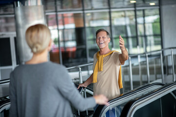 Man walking up escalator gesturing in greeting