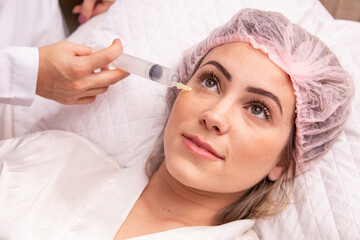 closeup of woman applying ozone to her face for cosmetic treatment.