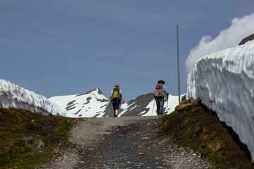 Backpacker hiker walking on panoramic trail with view on swiss alps with snow