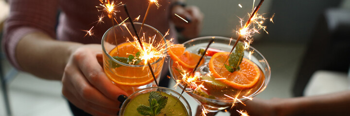 Goup of people holding cocktails in their hands with sparklers