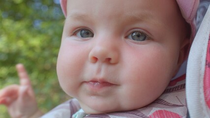 Portrait of a little girl in a stroller. She looks into the camera, focus of attention. Waiting for the parent. Blue eyes.
