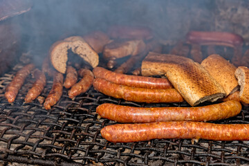 Grilled sausages on grill with smoke and flam