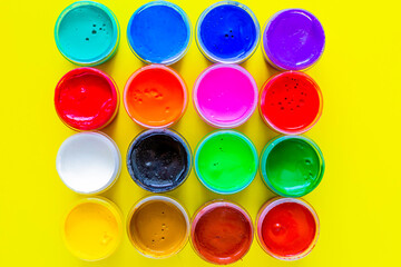 Many bright cans of paint stand together on a yellow background close-up. top view, flat lay, copy space, isolate.