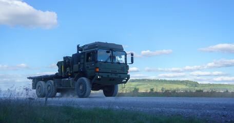 British army MAN HX58 9 Tonne 6x6 Cargo Medium Mobility logistics service vehicle in action, blue sky with scattered white clouds