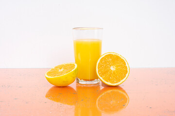 Glass of orange juice with fresh fruits on blue background