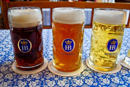 Munich, Germany: Hofbrauhaus (Hofbräuhaus) beer - Dunkel (dark), Helles  (lager), Radler (mixed with lemonade), Weißbier (wheat) in "HB" beer steins  (called maß) on blue and white tablecloth. Stock Photo | Adobe Stock