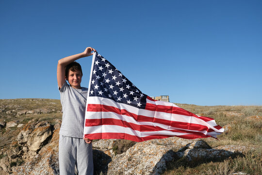 A boy holding waving US flag, beeng a patriot concept