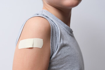 An arm of a boy with adhesive bandage plaster on it after vaccination. Injection covid vaccine,...