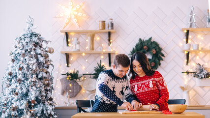 happy family married couple bakes christmas cookies and laughs in the kitchen decorated for the feast