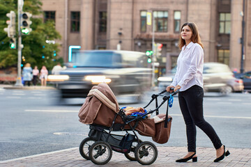 Woman with child in baby carriage walks during maternity leave.