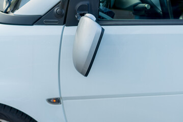 Broken off side rearview mirror on car. White automobile on road after accident.